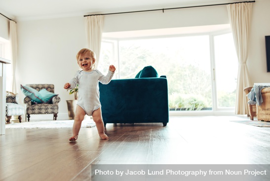 c1-np_Happy young child learning to walk on wood floor of home_42qee5_free