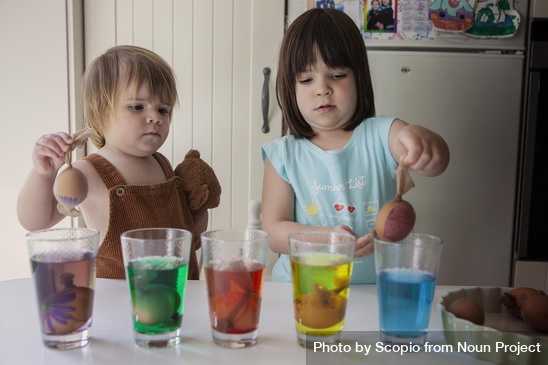 c6-np_Girl and toddler putting eggs in coloring glasses in the kitchen at home_0KQ8V4_free